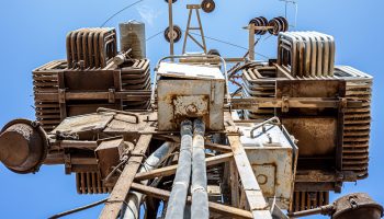 Old rusted high voltage transformer bottom view. High voltage circuit breaker in an electrical substation.